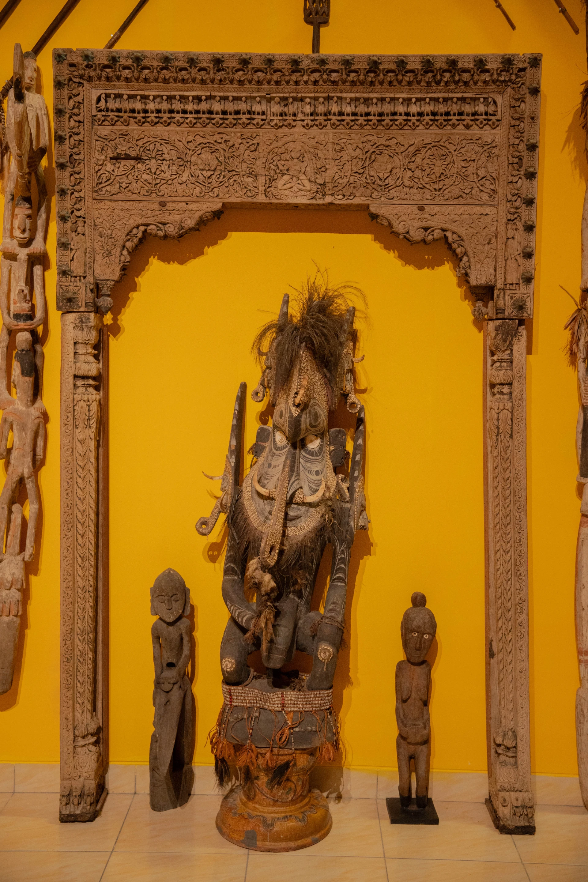 Detailed view of ceremonial mask and textiles and ancient weapons displayed together in the Scary Room, Museum Peter Bloch Collection.
